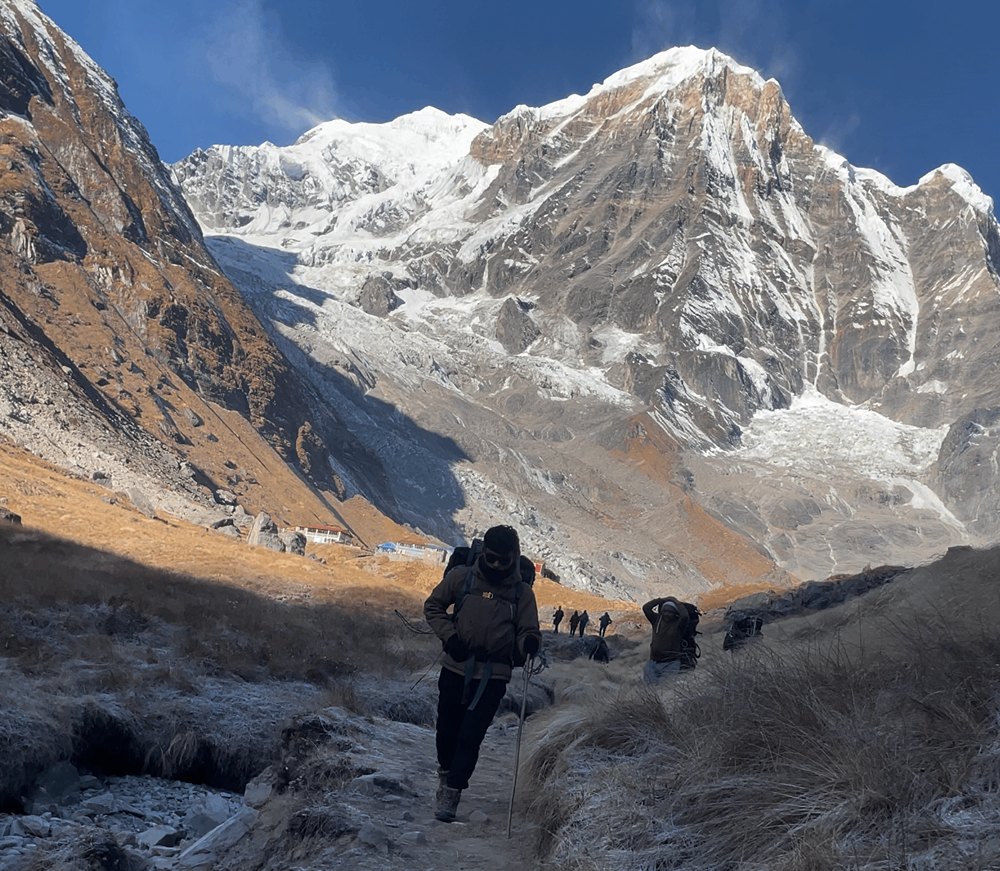 Trekkers starting their hike back from Annapurna Base Camp at dawn with soft morning light on snow peaks